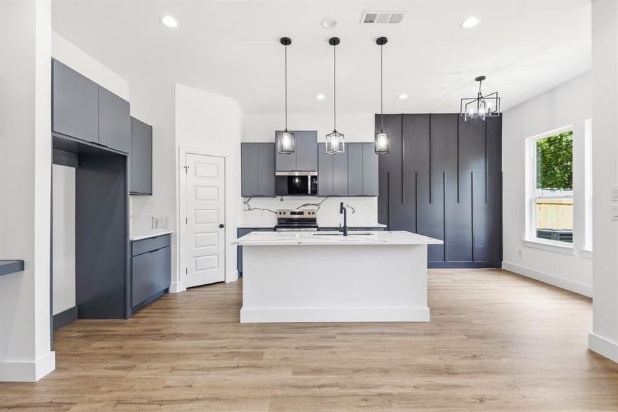 Modern kitchen featuring a central island with white quartz countertop and integrated sink Modern kitchen featuring a central island with white quartz countertop and integrated sink