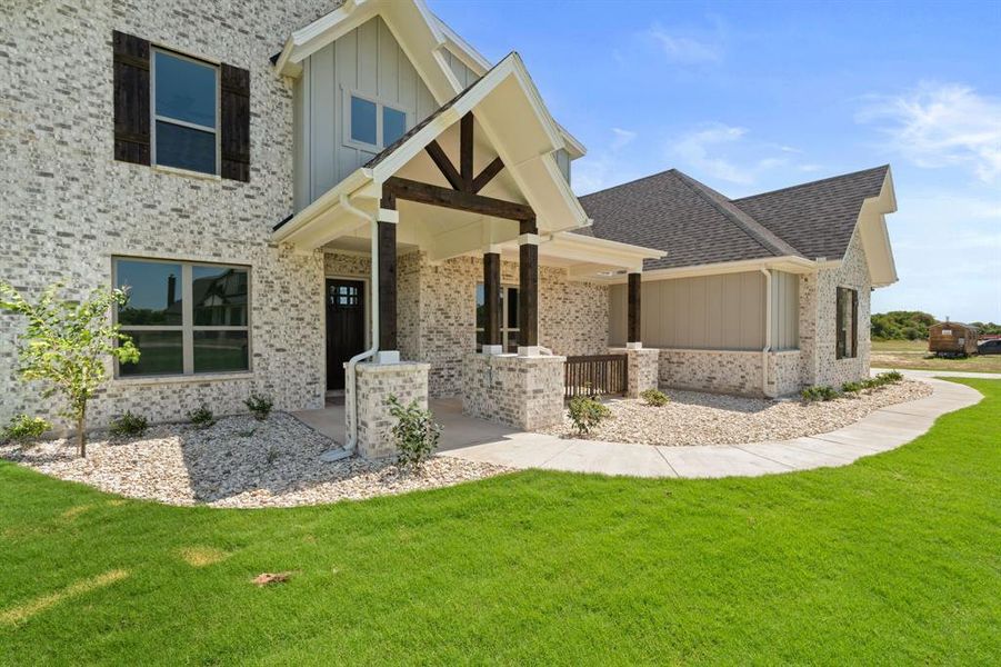 Craftsman house featuring a front yard, board and batten siding, a shingled roof, and brick siding Craftsman house featuring a front yard, board and batten siding, a shingled roof, and brick siding