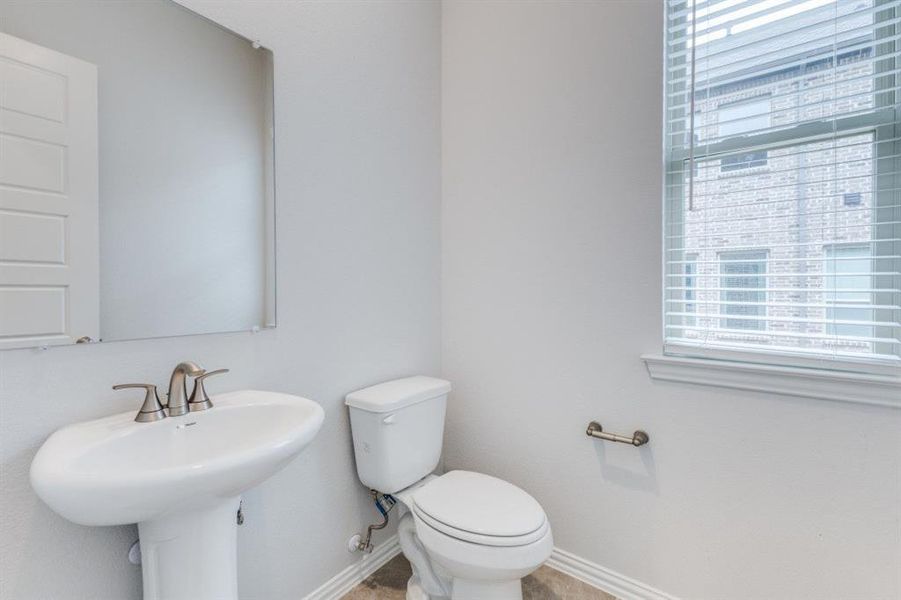 Half bathroom featuring toilet, baseboards, and a sink