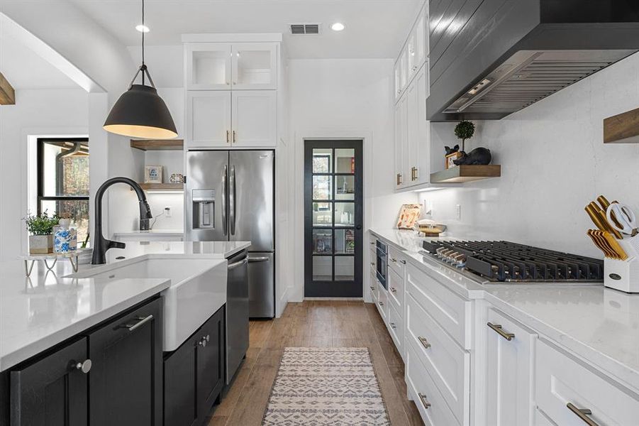 Kitchen with open shelves, visible vents, white cabinets, and wall chimney range hood Kitchen with open shelves, visible vents, white cabinets, and wall chimney range hood