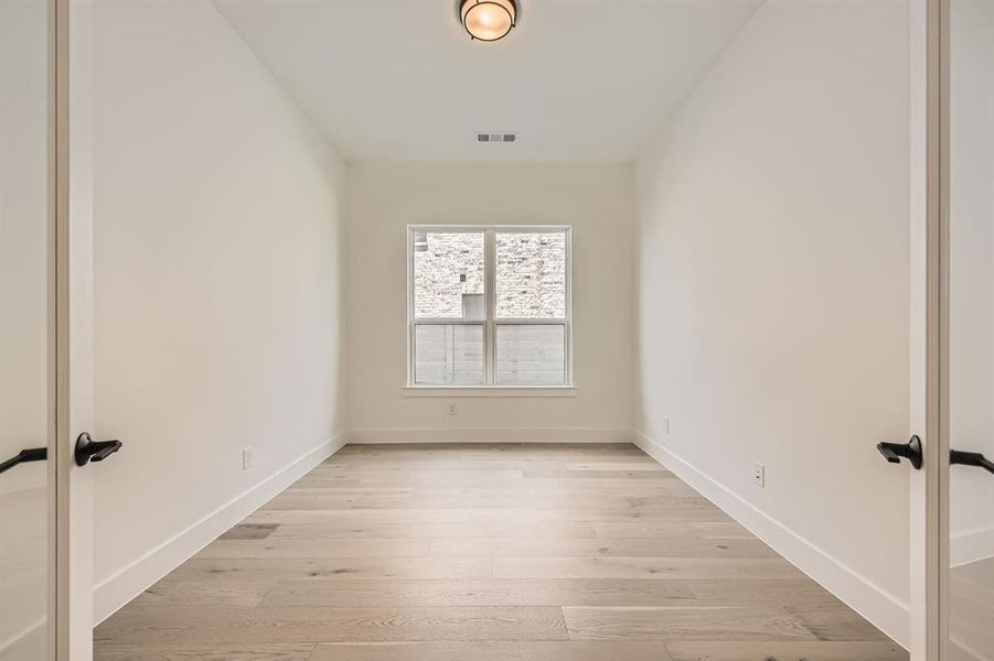 Spare room featuring french doors, light wood finished floors, and baseboards