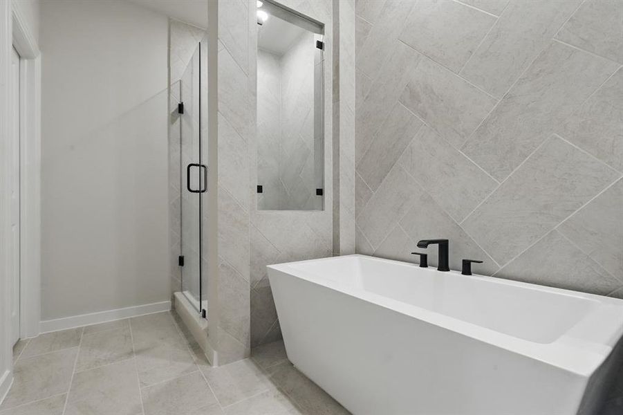 Full bath with tile walls, a freestanding tub, a shower stall, and light tile patterned floors