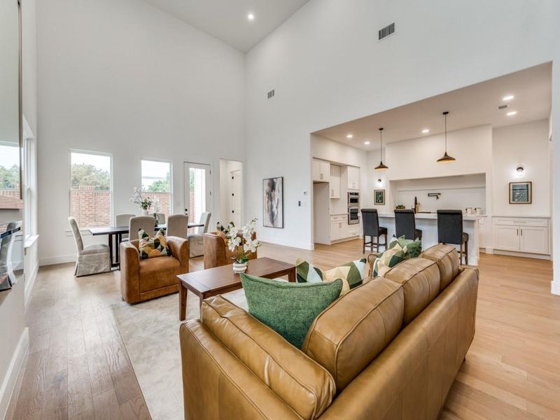 Living room with a towering ceiling and light hardwood / wood-style flooring