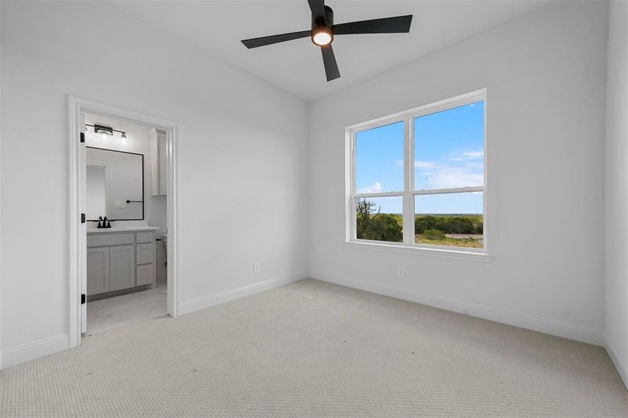 Unfurnished bedroom featuring light carpet, ensuite bathroom, sink, and ceiling fan