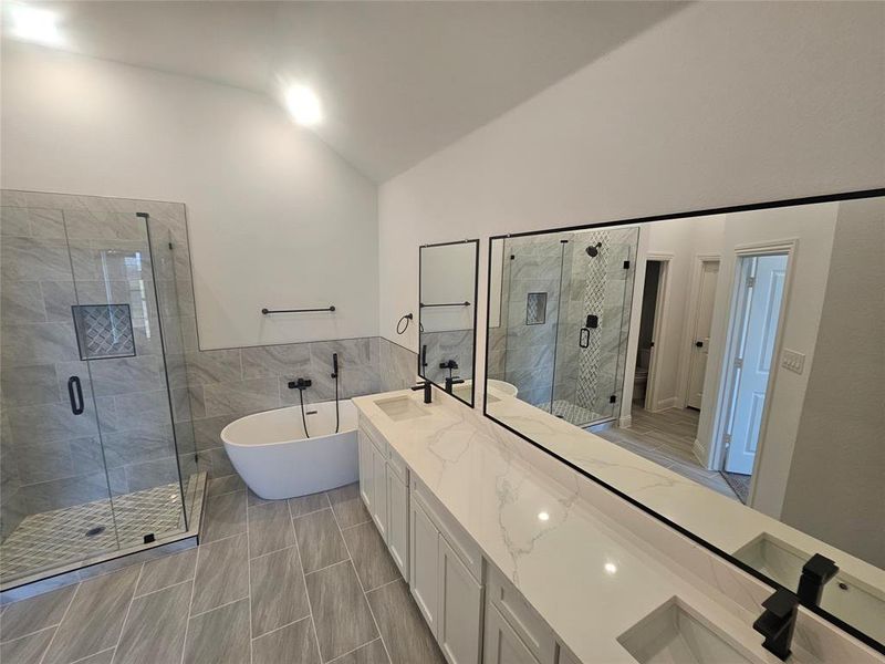 Bathroom featuring lofted ceiling, shower with separate bathtub, vanity, and tile walls