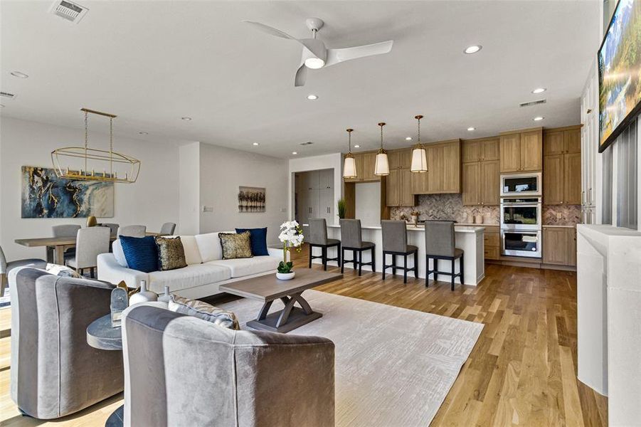 Living room with light hardwood / wood-style flooring and ceiling fan with notable chandelier