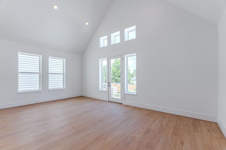 This room features a spacious, bright interior with high vaulted ceilings and light wood flooring. Large windows and a glass door let in plenty of natural light, enhancing the open feel.Photo Disclaimer: Photos are representative of the community and may depict a similar floor plan, model home, or previously completed residence. This room features a spacious, bright interior with high vaulted ceilings and light wood flooring. Large windows and a glass door let in plenty of natural light, enhancing the open feel.Photo Disclaimer: Photos are representative of the community and may depict a similar floor plan, model home, or previously completed residence.