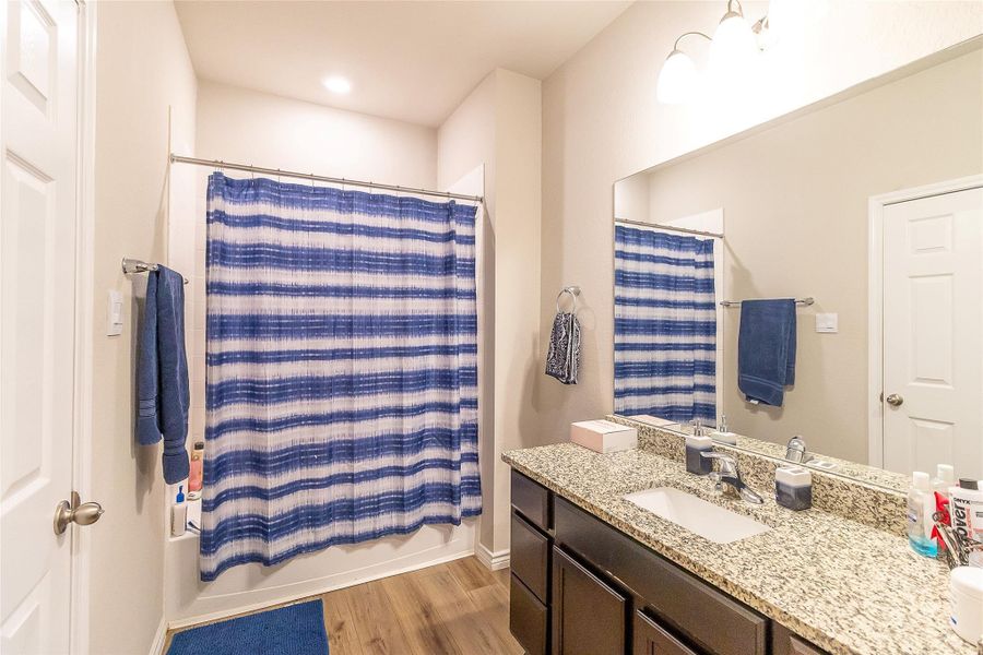 Granite counters and wood flooring provide a polished look in this well-appointed bathroom.