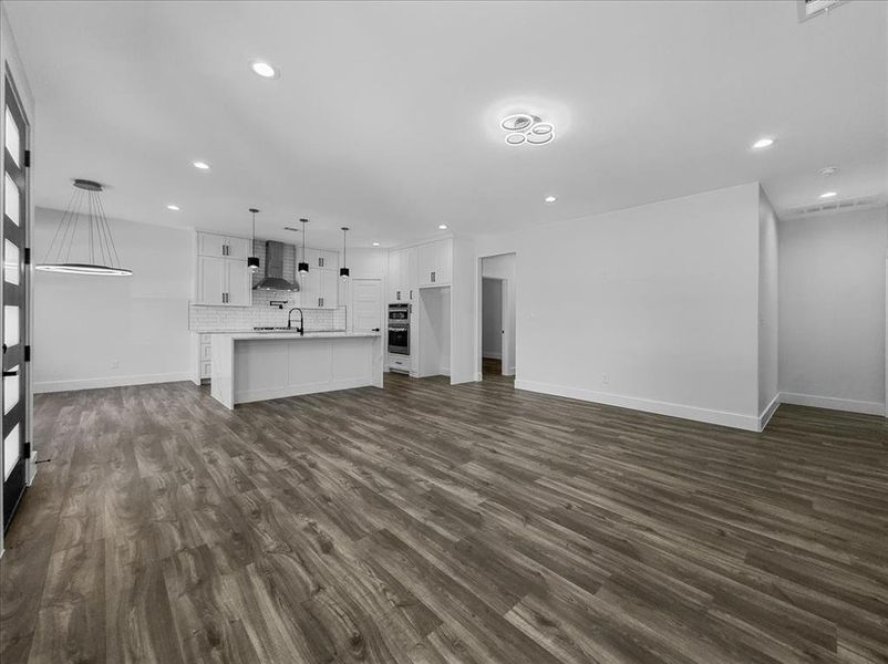 Unfurnished living room featuring dark wood-style floors and recessed lighting Unfurnished living room featuring dark wood-style floors and recessed lighting