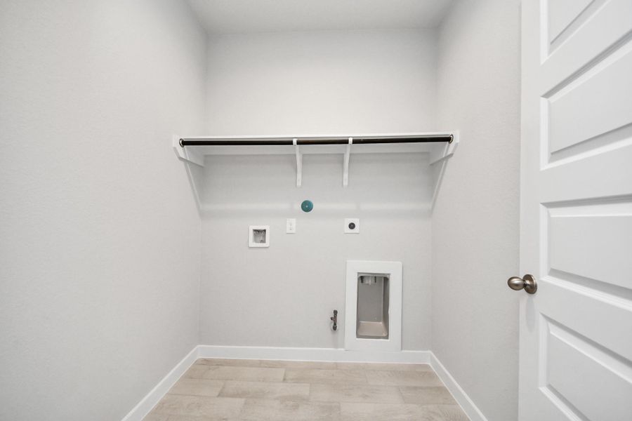 A perfect blend of functionality and comfort. Capture the essence of easy living with a first-floor laundry room, thoughtfully equipped with shelving for effortless organization. Both electric and gas connections available. Sample photo of completed home with similar floor plan. Actual colors and selections may vary.