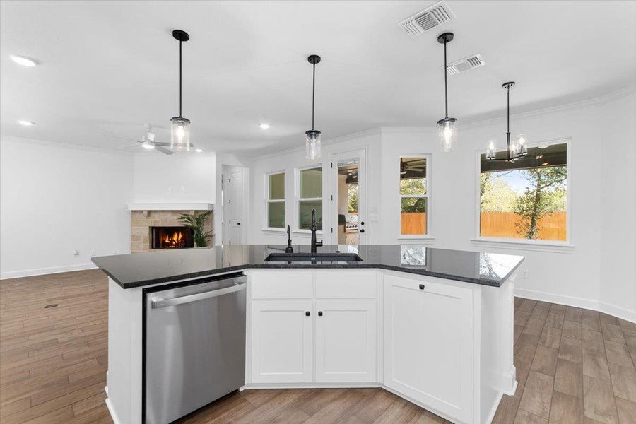 Kitchen with stainless steel dishwasher, a sink, ornamental molding, a ceiling fan, and a tiled fireplace Kitchen with stainless steel dishwasher, a sink, ornamental molding, a ceiling fan, and a tiled fireplace