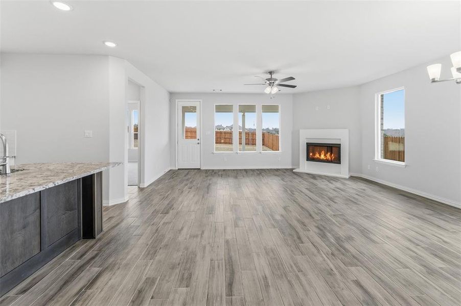Unfurnished living room with a glass covered fireplace, light wood finished floors, plenty of natural light, and recessed lighting