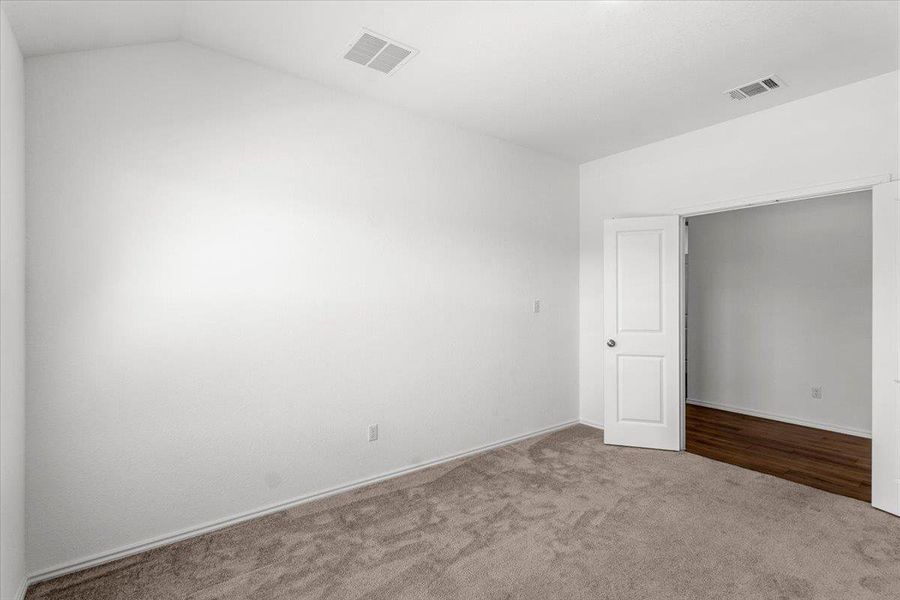 Carpeted empty room featuring lofted ceiling and baseboards
