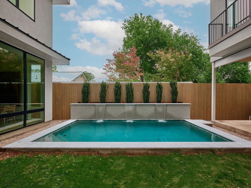 Compact rectangular swimming pool featuring a waterfall wall with three water features