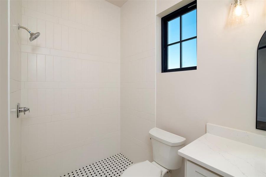 Bathroom with vanity, toilet, and tiled shower