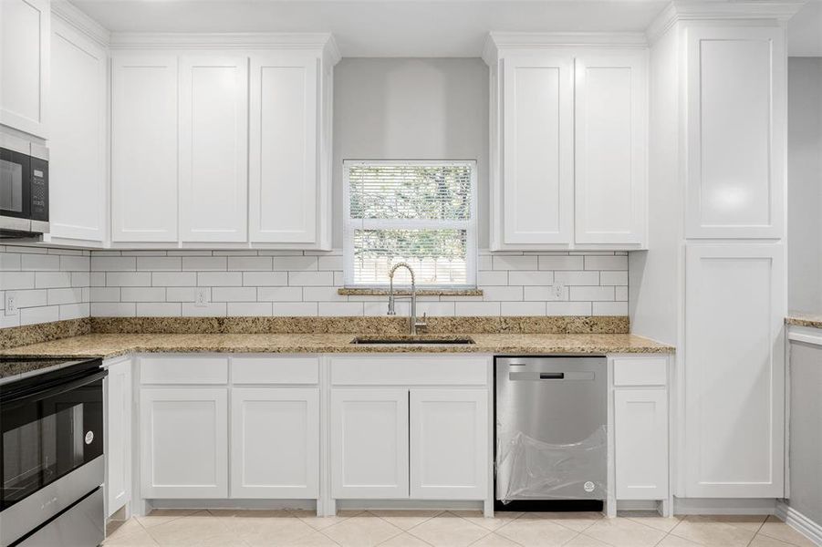 Kitchen featuring backsplash, white cabinetry, sink, and appliances with stainless steel finishes