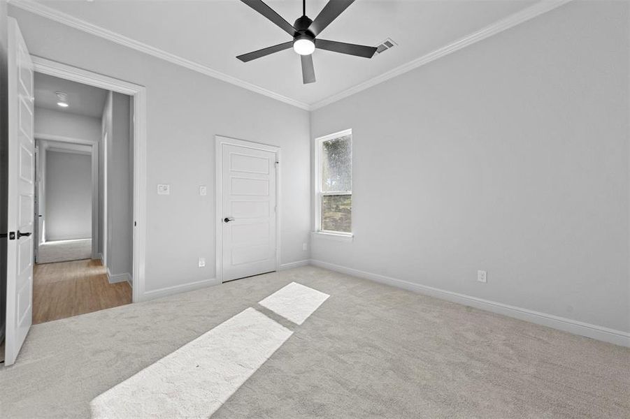 Bedroom featuring ceiling fan, light colored carpet, and ornamental molding