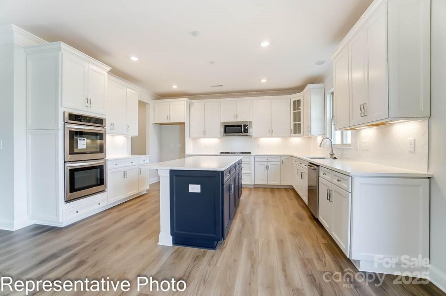 This home features white kitchen cabinets with gray island and quartz countertops