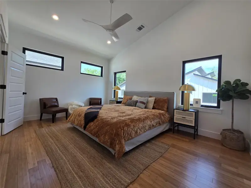 Bedroom featuring hardwood / wood-style flooring, recessed lighting, visible vents, and high vaulted ceiling Bedroom featuring hardwood / wood-style flooring, recessed lighting, visible vents, and high vaulted ceiling