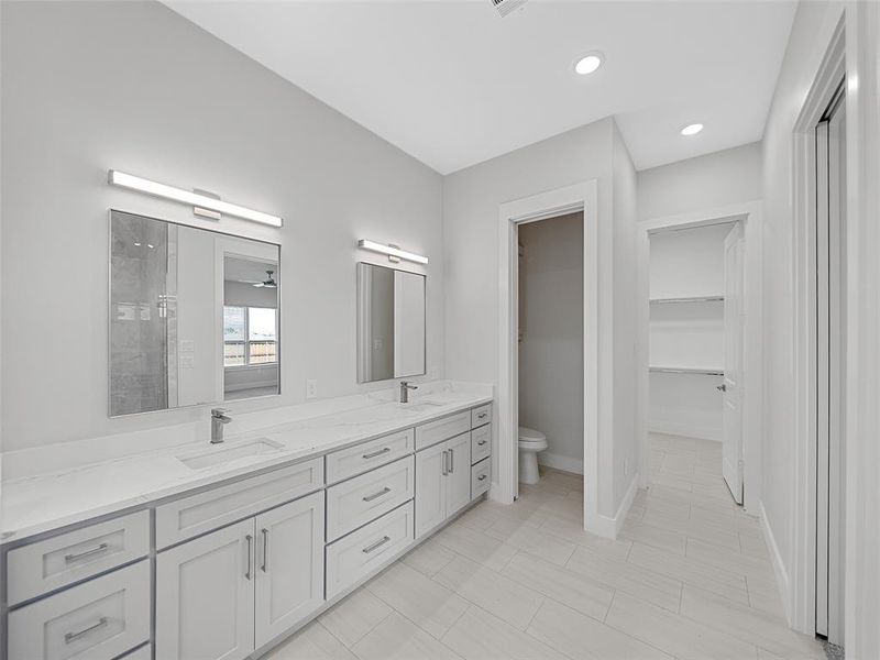 Primary Bathroom with tile patterned floors, ceiling fan, double sink vanity, and toilet