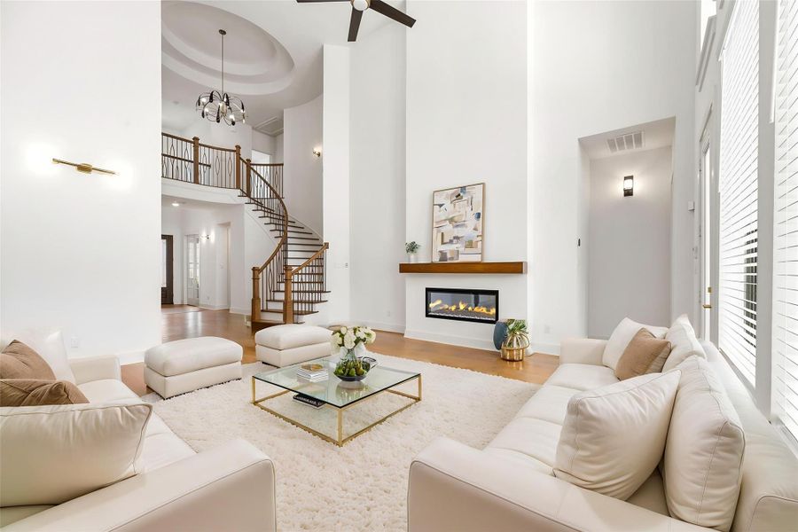 This majestic living area centers around a dramatic spiral staircase and a sleek, custom linear fireplace , creating a balanced focal point for formal entertaining on the rich engineered wood flooring.