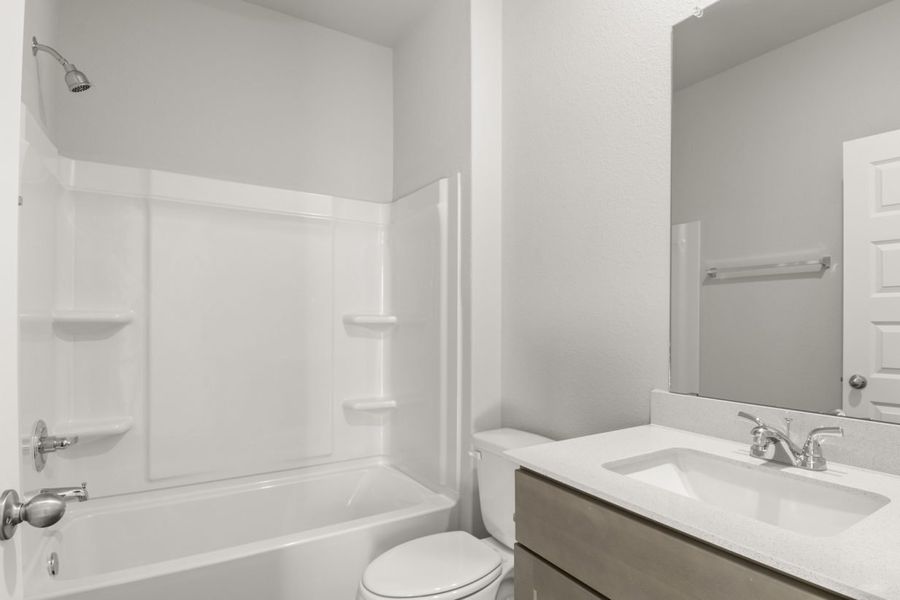 Image of a white vinyl shower and tub, a white vanity and a mirror