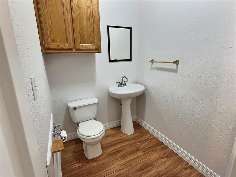 Bathroom with dark wood finished floors and a textured wall