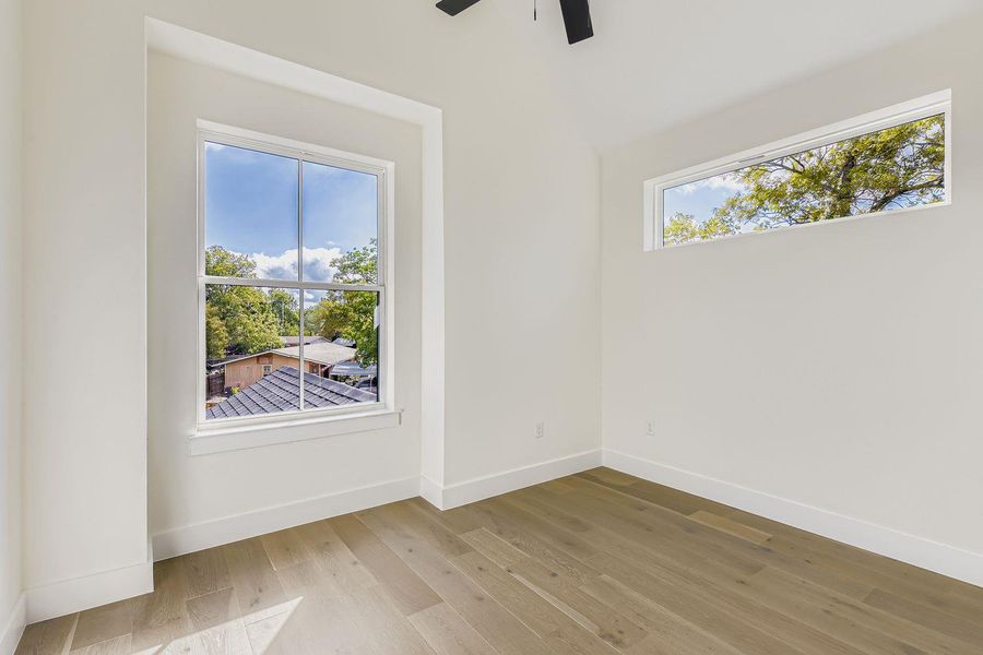 Empty room featuring light wood-style floors and a ceiling fan Empty room featuring light wood-style floors and a ceiling fan