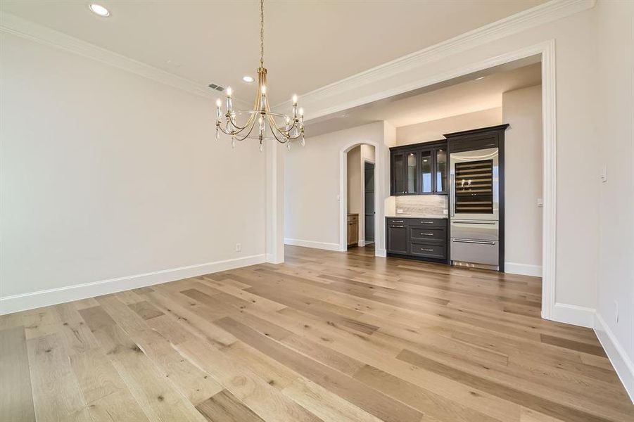 Unfurnished dining area featuring ornamental molding, an inviting chandelier, and light hardwood / wood-style floors