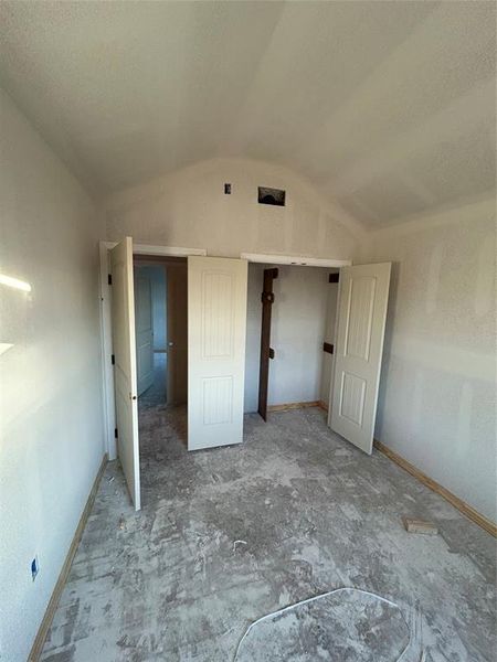 Unfurnished bedroom with vaulted ceiling and baseboards