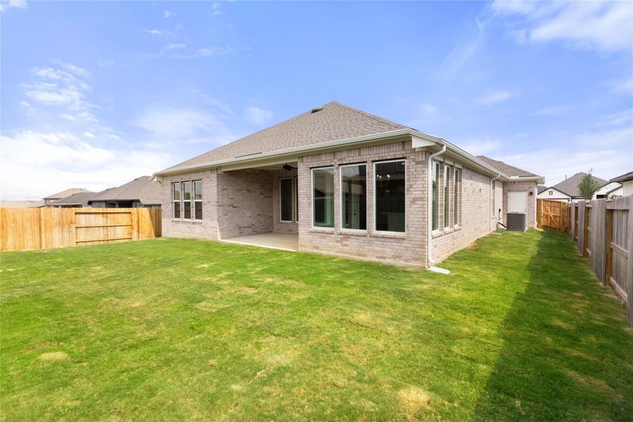 Rear view of property with brick siding, a fenced backyard, a patio area, and a shingled roof
