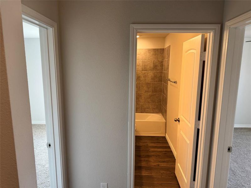 Hallway with dark wood-type flooring and baseboards