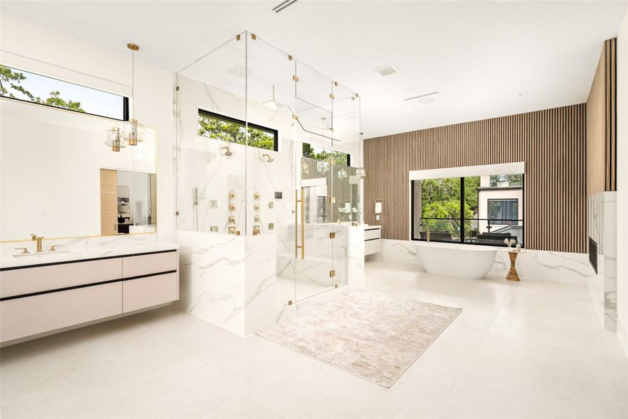 Light-filled primary bath with a sculptural freestanding tub, central glass shower, and refined material palette.