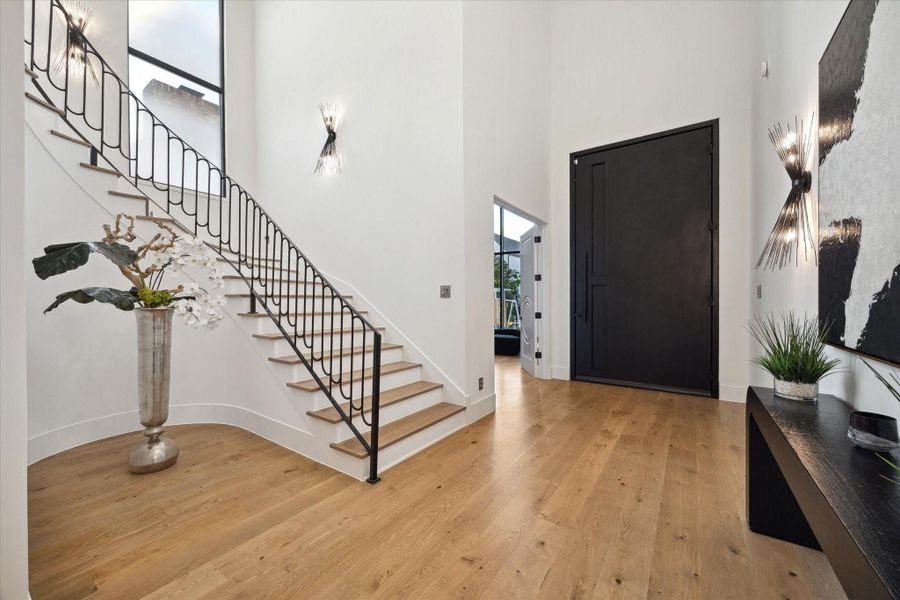 Two story entry/foyer with grand stair case and elegant wall sconces