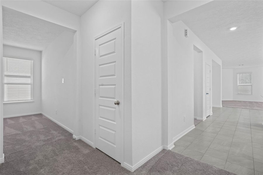 This view showcases the entrance to the Den, coat closet, laundry room, and entrance to kitchen and Great Room.