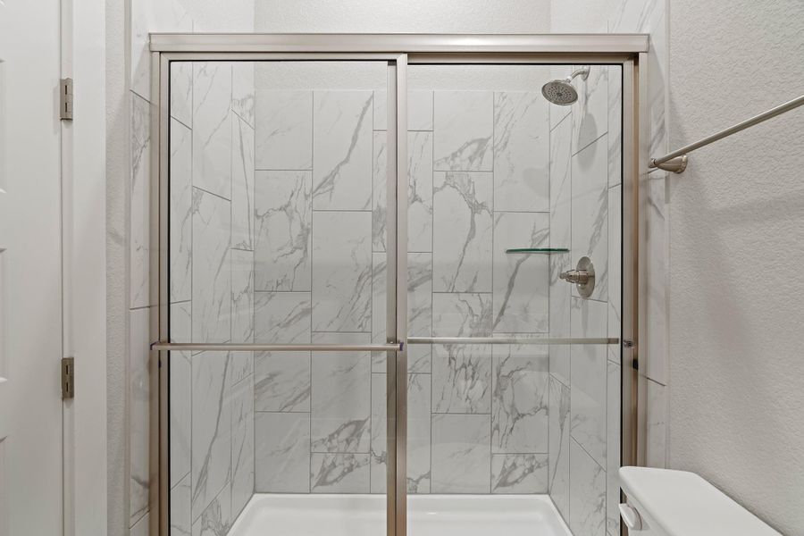 Full bath with a textured wall and a marble finish shower Full bath with a textured wall and a marble finish shower