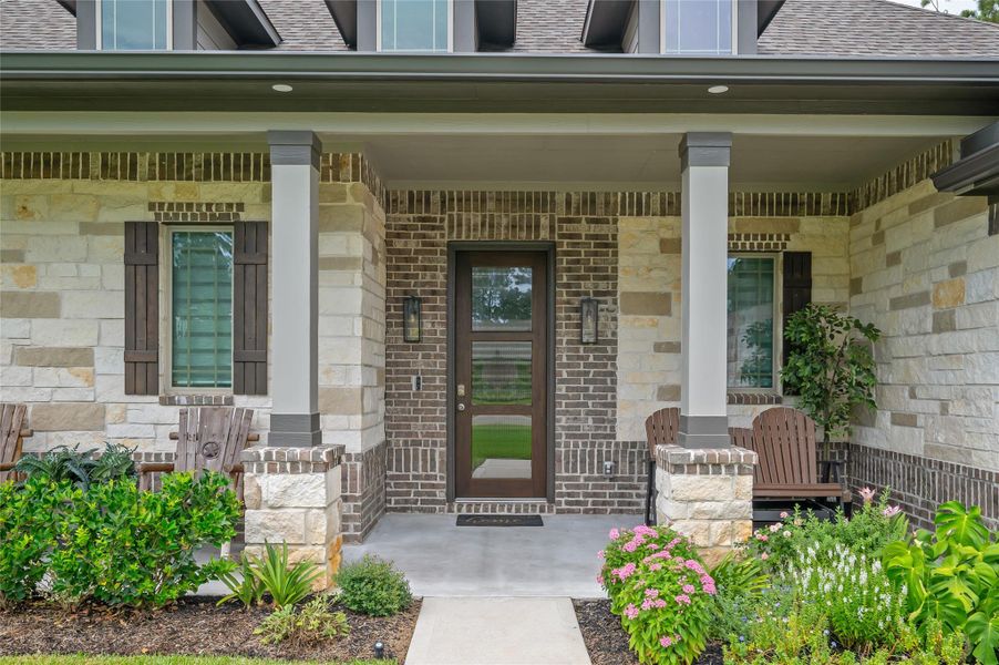 Inviting covered front porch with a modern front door and lush landscaping.