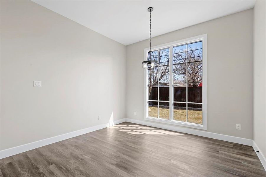 Unfurnished dining area with dark wood-type flooring and an inviting chandelier