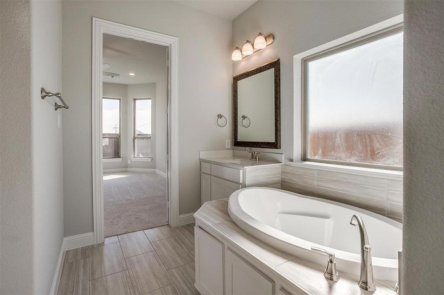 Bathroom featuring plenty of natural light, a bathtub, and vanity