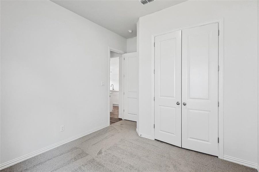 Unfurnished bedroom featuring light carpet and a closet