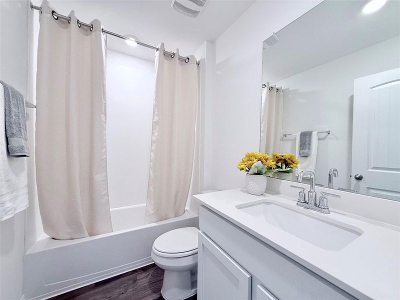 Full bathroom featuring vanity, dark wood-style floors, and shower / bath combo with shower curtain Full bathroom featuring vanity, dark wood-style floors, and shower / bath combo with shower curtain
