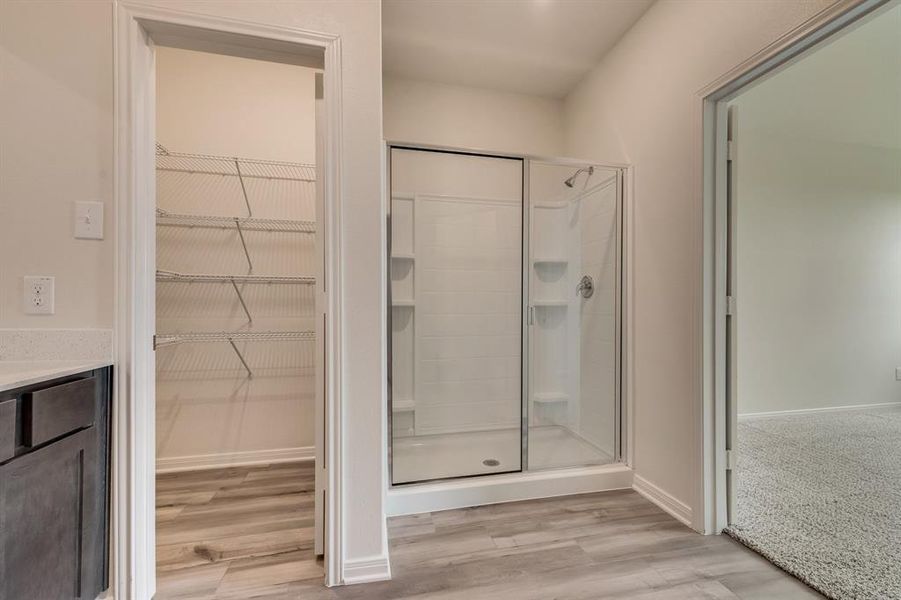 Bathroom with a shower with shower door, wood-type flooring, and vanity