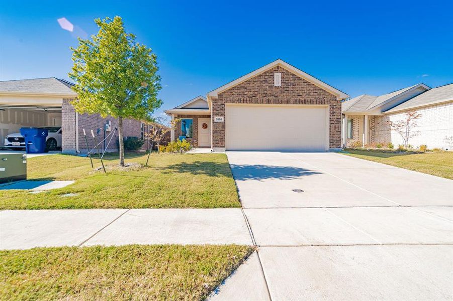 View of front of home featuring brick siding, a front yard, concrete driveway, and a garage