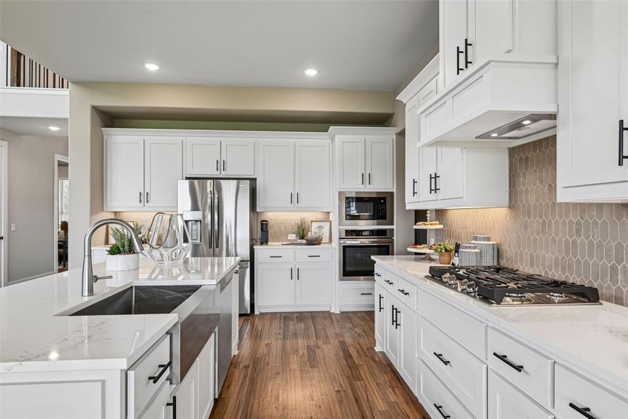 Kitchen with white cabinets, quartz countertops, stainless steel appliances, gas cooktop, and dark hardwood floors Kitchen with white cabinets, quartz countertops, stainless steel appliances, gas cooktop, and dark hardwood floors