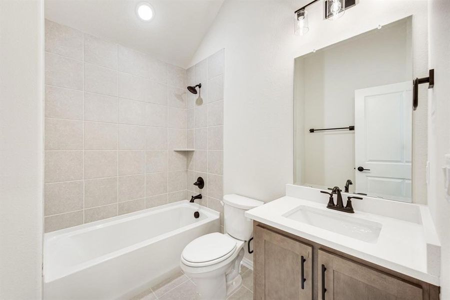 Bathroom featuring shower / washtub combination, vanity, light tile patterned floors, and lofted ceiling