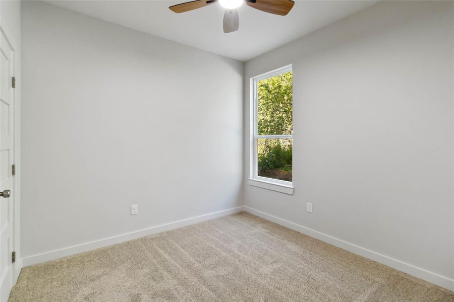 Carpeted spare room with baseboards and ceiling fan