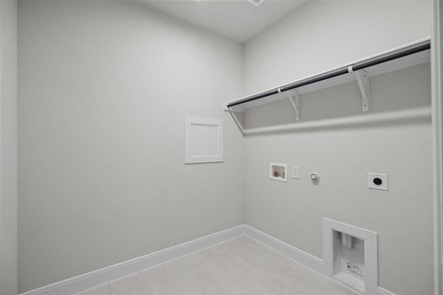 Laundry room featuring light grey walls, white baseboards, and light-toned tile flooring Laundry room featuring light grey walls, white baseboards, and light-toned tile flooring