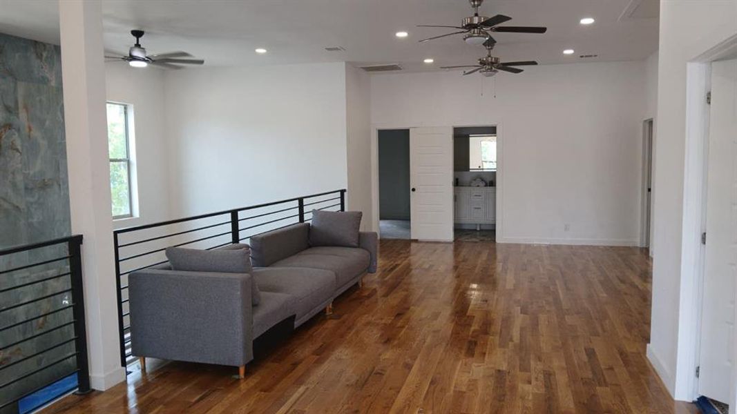 Expansive open-concept space featuring wood-finish flooring, recessed lighting, and multiple ceiling fans