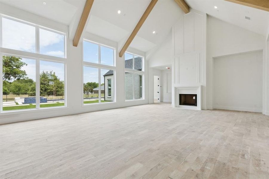 Natural light fills the great room with a cathedral ceiling displaying beautiful wood beams, two-story fireplace, and floor to ceiling windows overlooking your outdoor retreat.