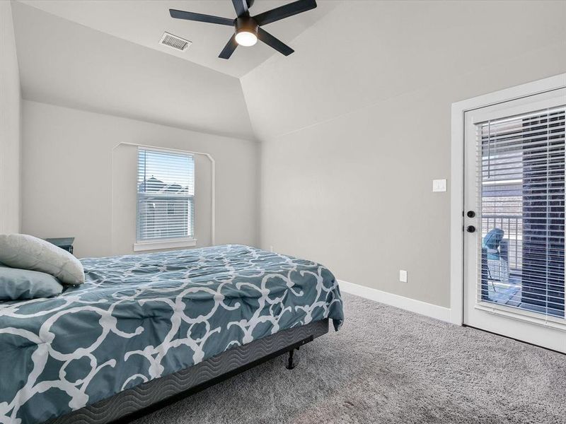 Bedroom featuring ceiling fan, vaulted ceiling, carpet floors, and access to exterior Bedroom featuring ceiling fan, vaulted ceiling, carpet floors, and access to exterior